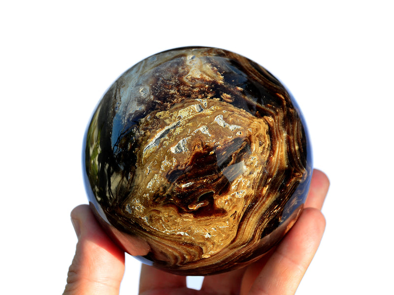 One chocolate calcite sphere 75mm on hand with white background