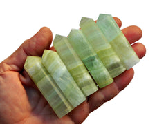Six pistachio calcite faceted crystal points 50mm-55mm on hand with white background