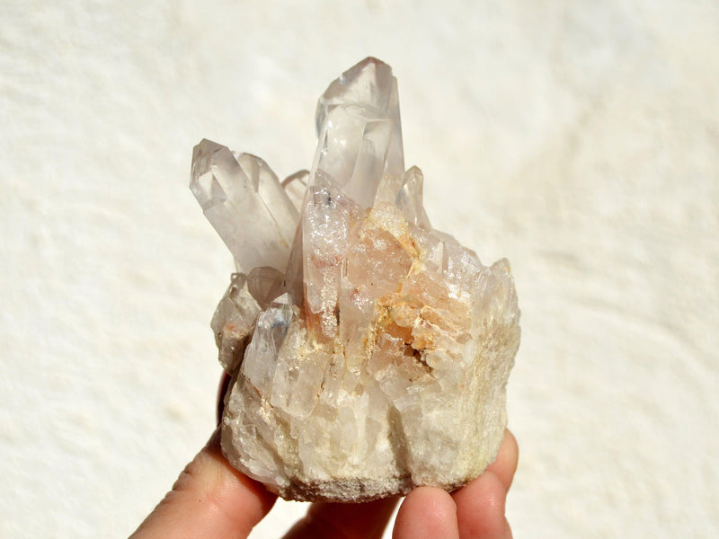 One rough crystal quartz cluster on hand with white background