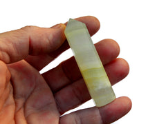 One pistachio calcite faceted crystal point 55mm on hand with white background