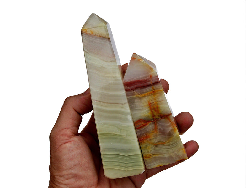 Two large pink banded onyx obelisks stones different sizes on hand with white background