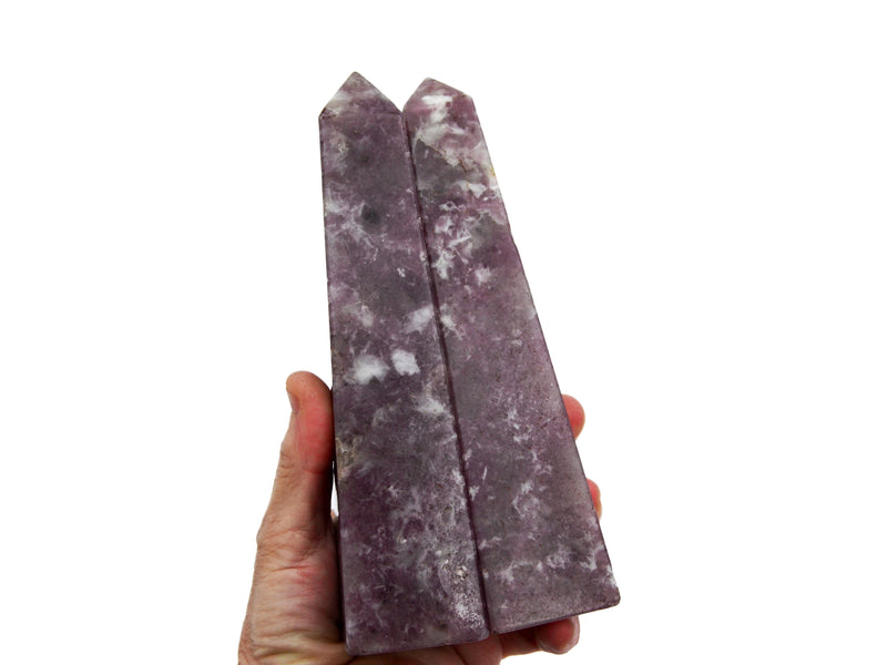 Two arge lepidolite crystal obelisks 150mm on hand with white background