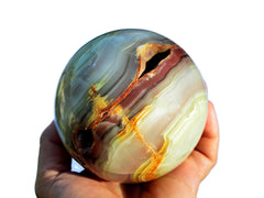 One large druzy pink banded onyx sphere crystal 90mm on hand with white background