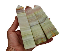 Three large pink banded onyx obelisks crystals 130mm on hand with white background