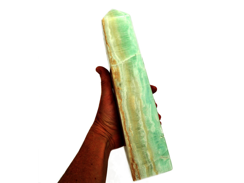 An extra large caribbean calcite obelisk 270mm on hand with white background