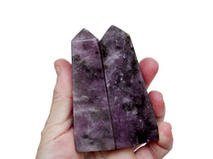 Two lepidolite crystal obelisks 90mm on hand with white background