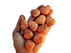 Ten small orange calcite heart crystals 30mm on hand with white background