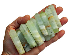 Several green pistachio calcite crystal points 50mm-55mm on hand with white background