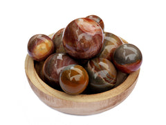 Several multicolor polychrome jasper sphere crystals 40mm - 60mm inside a wood bowl on white background