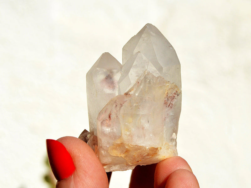 Raw crystal quartz cluster on hand with white background
