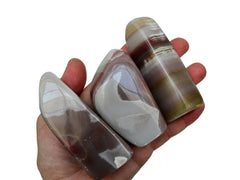 Three pink banded onyx free forms 70mm-80mm on hand with white background