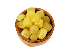 Some yellow calcite tumbled stones 25mm-30mm inside a wood bowl on white background