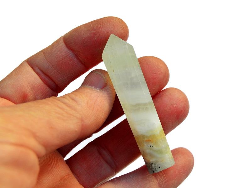 One pistachio calcite crystal point 50mm on hand with white background 