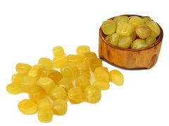 Some lemon calcite tumbled stones inside a wood bowl with some crystals outside arround on white background