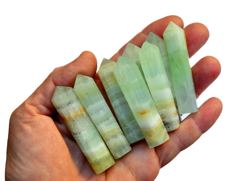 Some green pistachio calcite faceted crystal points 50mm-55mm on hand with white background