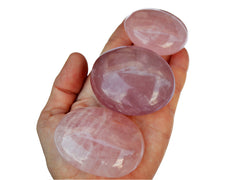 Three pink quartz palm stones 70mm-40mm on hand with white background