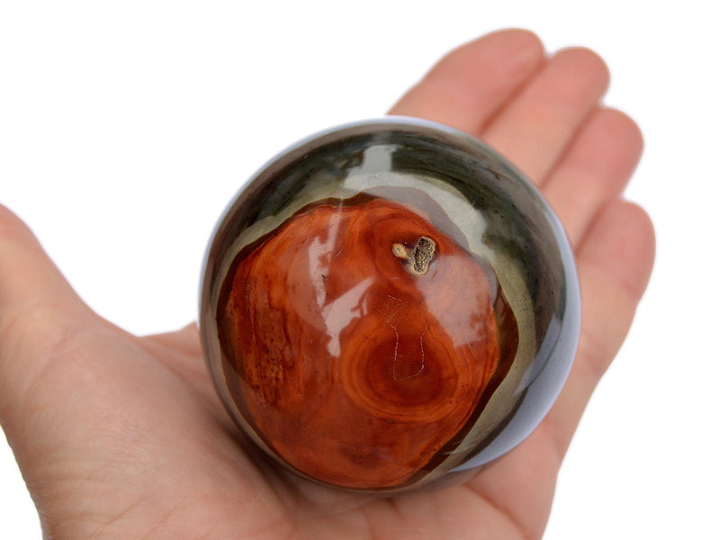 One red and gray desert jasper crystal ball 55mm on hand with white background