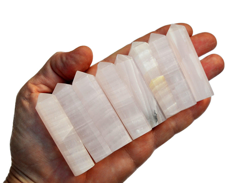 Eight pink mangano calcite faceted crystal points 55mm-60mm on hand with white background