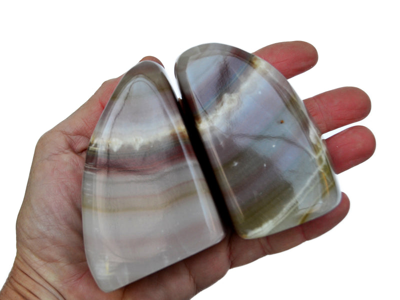 Two large pink banded onyx stones 100mm-110mm on hand with white background