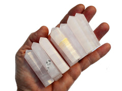 Eight mini pink mangano calcite faceted crystal towers 55mm-60mm on hand with white background