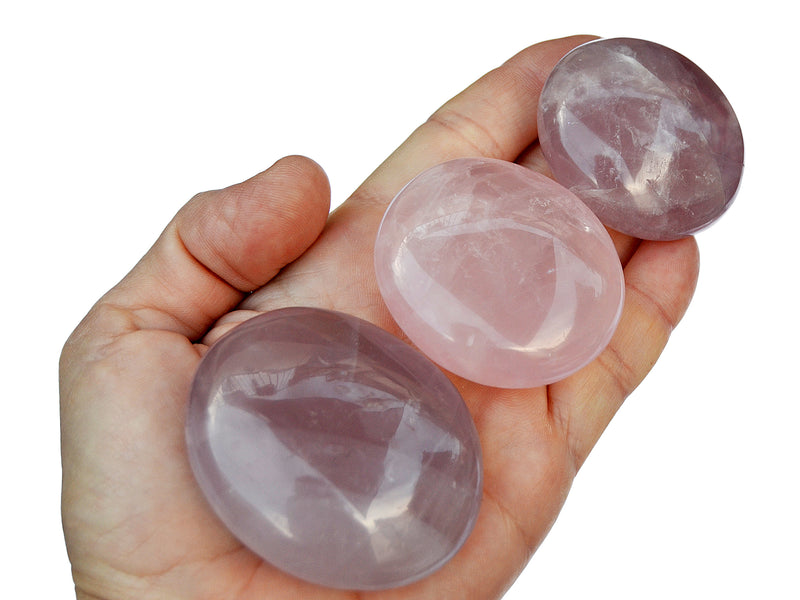 Three rose quartz palm stones 70mm-40mm on hand with white background