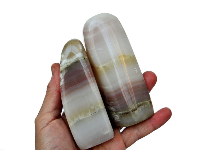 Two large pink banded onyx free form 90mm-100mm on hand with white background