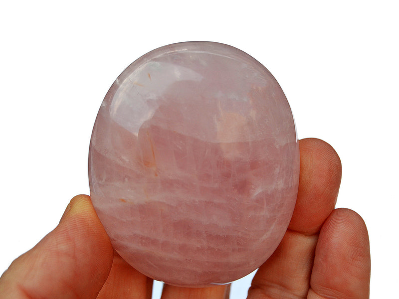 One rose quartz palm stone 60mm on hand with white background