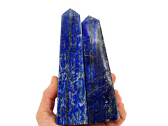 Two large lapis lazuli obelisks 140mm-150mm on hand with white bckground