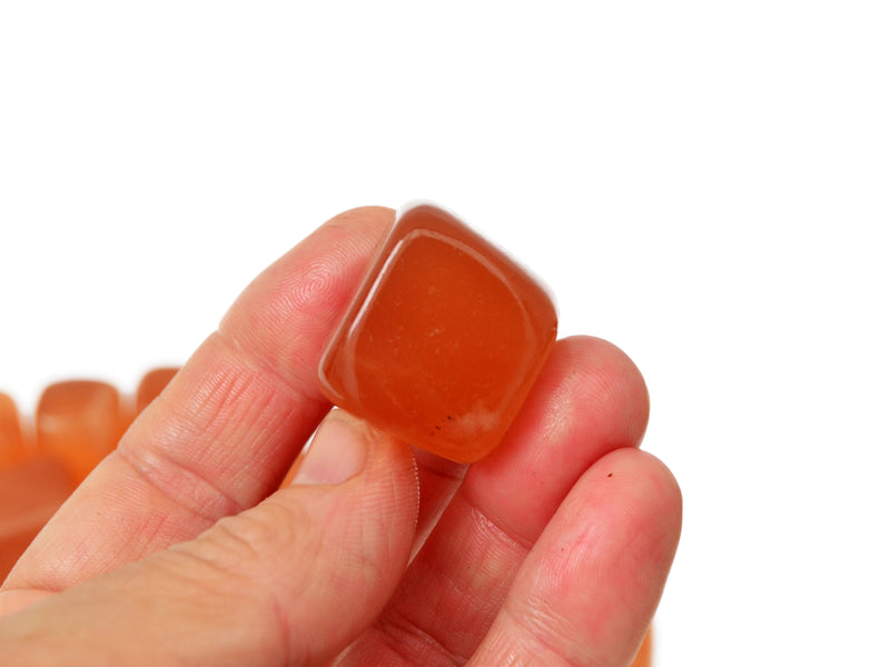 One honey calcite tumbled  stone on hand with white background 