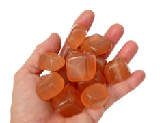 Eleven some honey calcite tumbled minerals on hand with white background