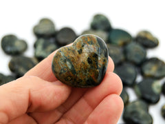 One ocean jasper heart crystal 35mm on hand with background with some stones on white