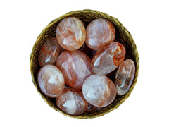 Several fire quartz crystal palm stones 40mm-70mm inside a straw basket on white background