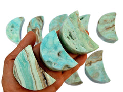 Blue aragonite shapped moon stones 65mm on hand with background with some moons on white