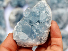 Blue celestite druzy crystal 60mm on hand with background with some crystals 