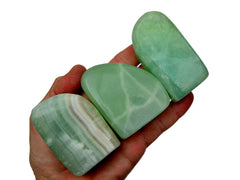 Three pistachio calcite free form minerals 60mm-85mm on hand with white background