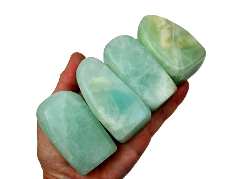 Four green pistachio calcite palm stones 60mm on hand with white background