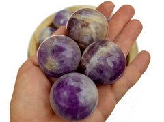 Four amethyst sphere stones 55mm - 60mm on hand with white background