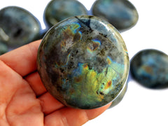 Large labradorite palm stone 60mm on hand with background with some crystals