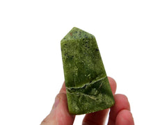 One green serpentine obelisk stone 60mm on hand with white background