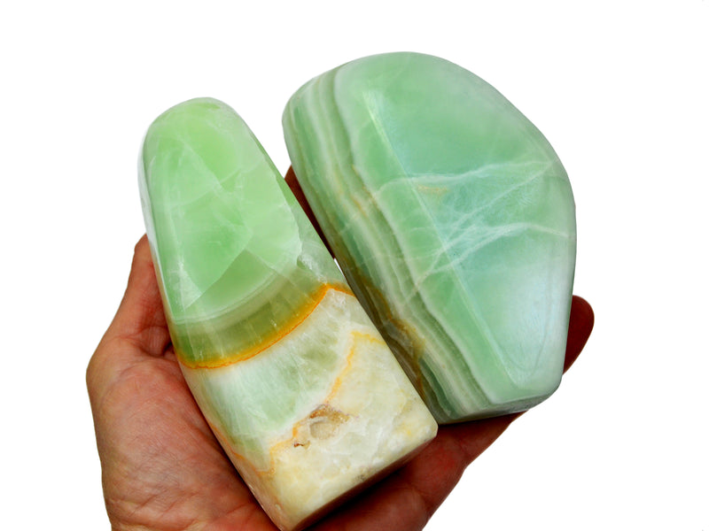 Two large pistachio calcite free form crystals 100mm-110mm on hand with white background