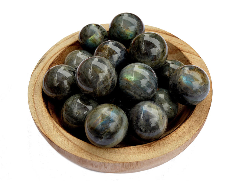 Several labradorite sphere crystals 25mm - 40mm inside a wood bowl on white background