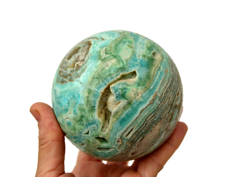 Large blue aragonite sphere 85mm on hand with white background