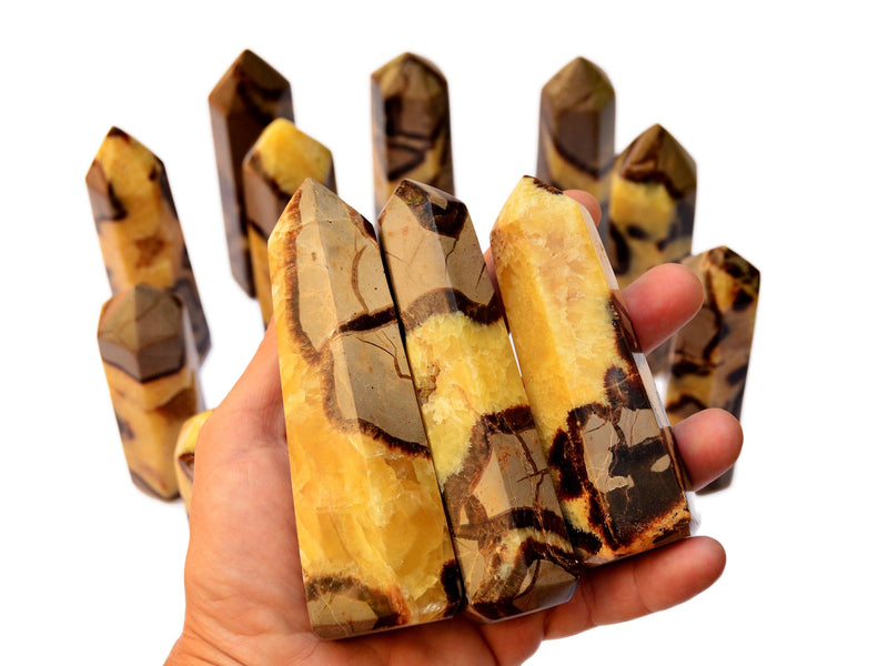 Three septarian faceted points 110mm on hand with background with some towers on white