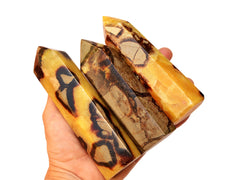 Three large yellow septarian towers 130mm on hand with white background