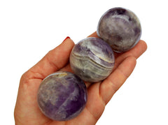 Three amethyst crystal spheres 55mm on hand with white background