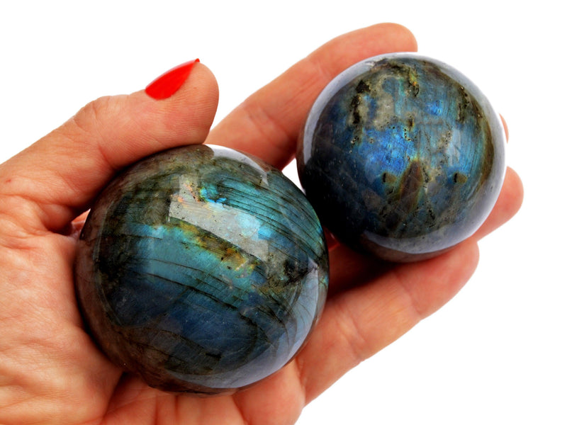 Two blue labradorite sphere crystals 45mm-60mm on hand with white background