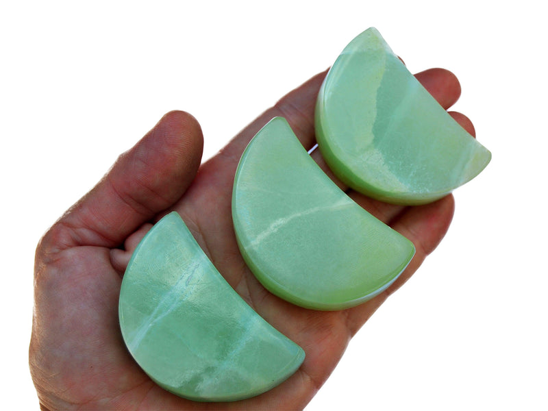 Three gren pistachio calcite moon shapped minerals 60mm on hand with white background