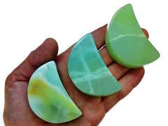 Three gren pistachio calcite moon carved crystals 60mm on hand with white background