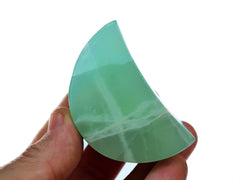 One green pistachio calcite moon crystal 60mm on hand with background with white background