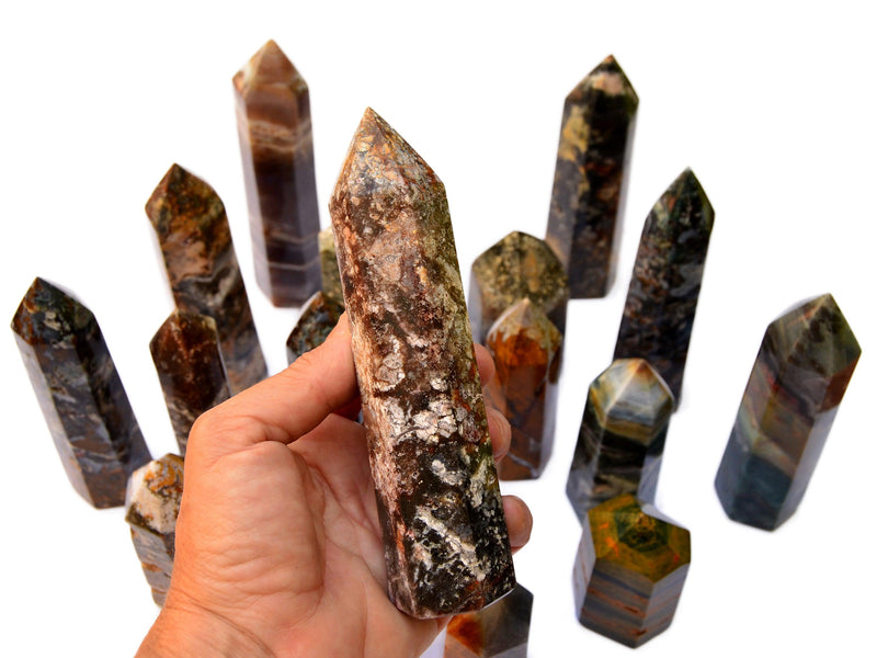 One ocean jasper obelisk 140mm on hand with background with some towers on white